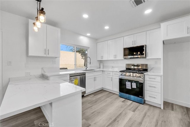 kitchen featuring stainless steel appliances, sink, hanging light fixtures, and white cabinets