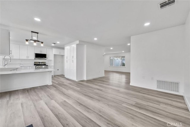 kitchen with appliances with stainless steel finishes, sink, light hardwood / wood-style floors, and white cabinets