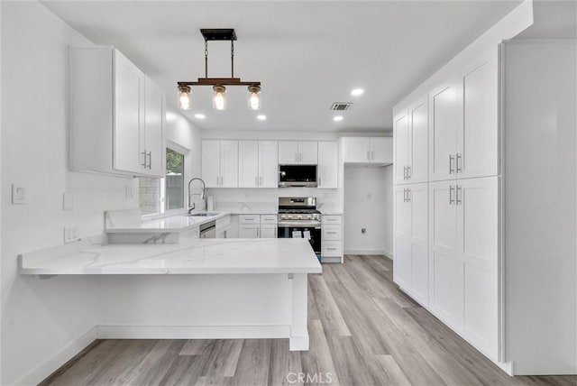 kitchen with pendant lighting, sink, appliances with stainless steel finishes, white cabinetry, and kitchen peninsula