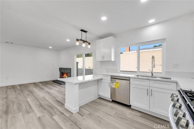 kitchen featuring sink, hanging light fixtures, kitchen peninsula, stainless steel appliances, and white cabinets