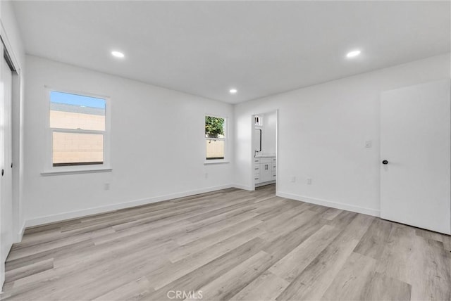 unfurnished bedroom featuring ensuite bathroom and light hardwood / wood-style floors