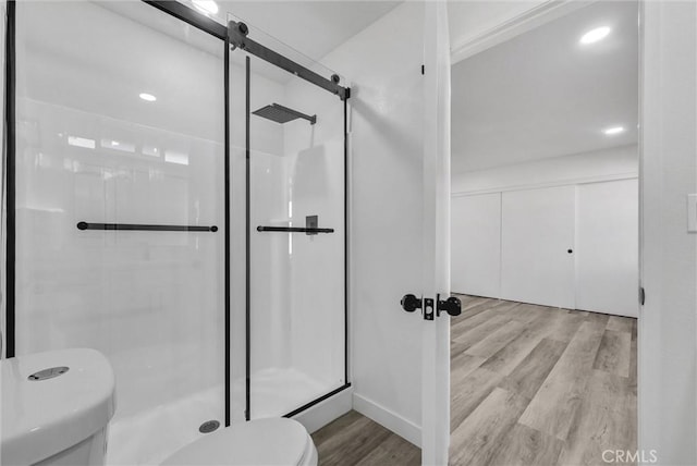 bathroom with hardwood / wood-style flooring, an enclosed shower, and toilet