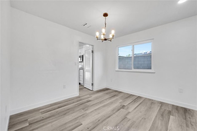 unfurnished room featuring a notable chandelier and light hardwood / wood-style floors