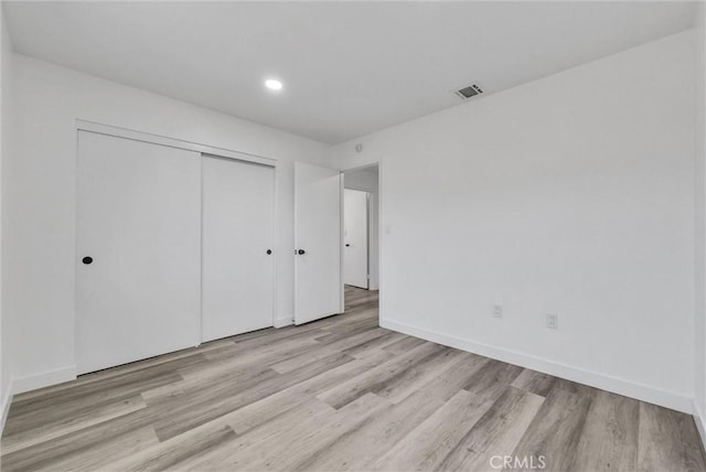 unfurnished bedroom with a closet and light wood-type flooring