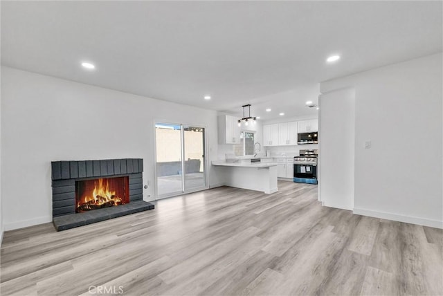 unfurnished living room featuring sink, a fireplace, and light wood-type flooring