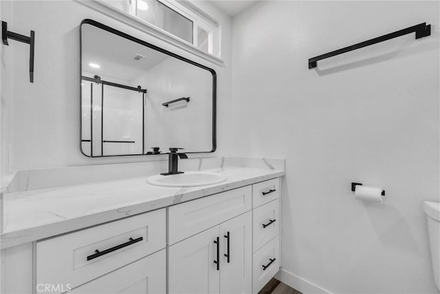 bathroom featuring vanity, an enclosed shower, and toilet