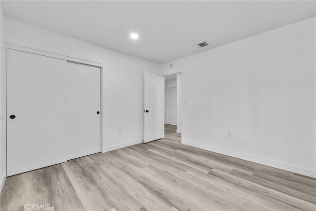 unfurnished bedroom with light hardwood / wood-style floors and a closet