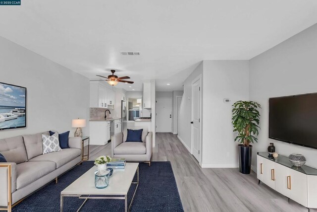 living room featuring sink, ceiling fan, and light wood-type flooring