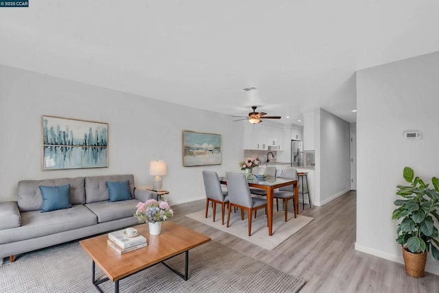 living room featuring ceiling fan, sink, and light hardwood / wood-style floors