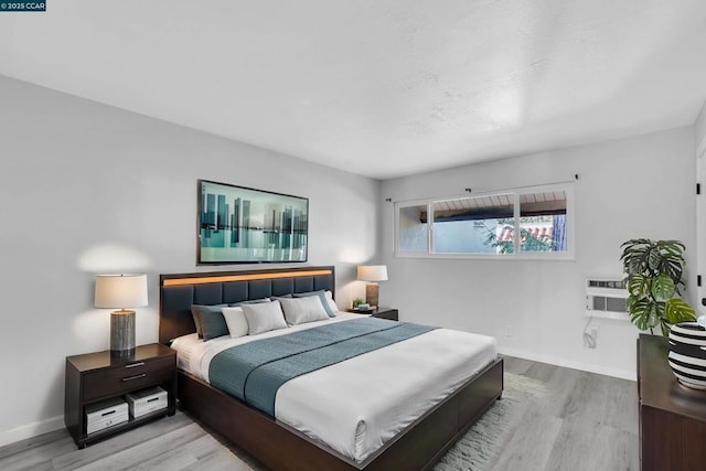 bedroom with a wall mounted AC and light wood-type flooring