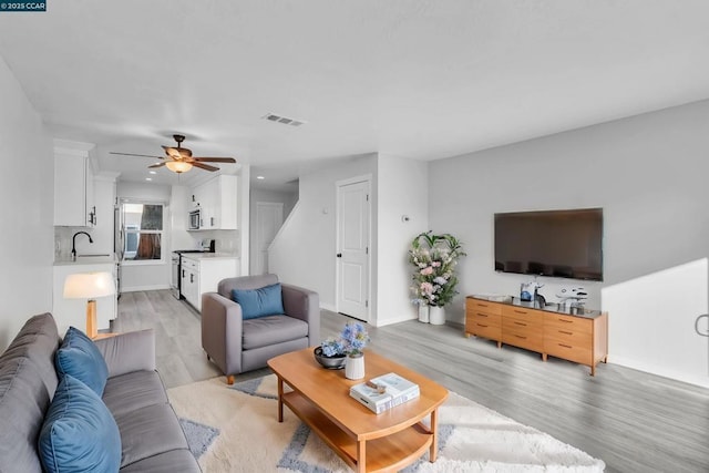 living room with ceiling fan, sink, and light hardwood / wood-style floors