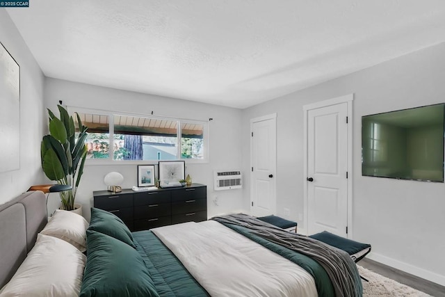 bedroom with hardwood / wood-style floors and an AC wall unit