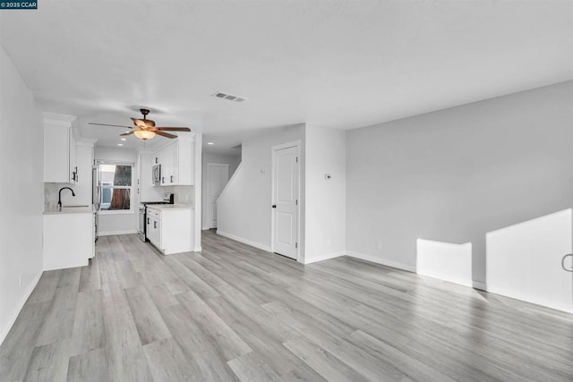 unfurnished living room with sink, ceiling fan, and light wood-type flooring