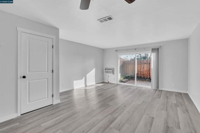 spare room featuring a wall mounted air conditioner, ceiling fan, and light wood-type flooring