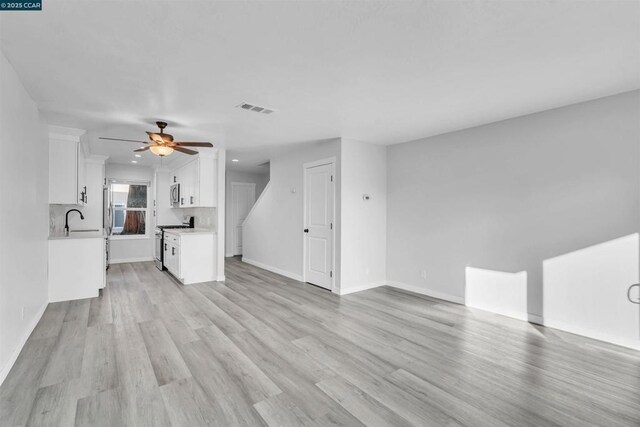 unfurnished living room featuring ceiling fan, light hardwood / wood-style floors, and sink