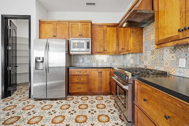 kitchen featuring tasteful backsplash, extractor fan, and appliances with stainless steel finishes