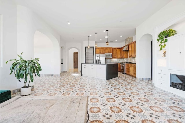 kitchen featuring sink, tasteful backsplash, a center island, appliances with stainless steel finishes, and pendant lighting