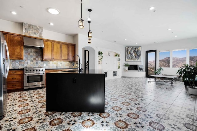 kitchen featuring decorative light fixtures, sink, decorative backsplash, high end stainless steel range, and wall chimney range hood