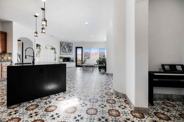 kitchen with tasteful backsplash, light tile patterned flooring, sink, and hanging light fixtures