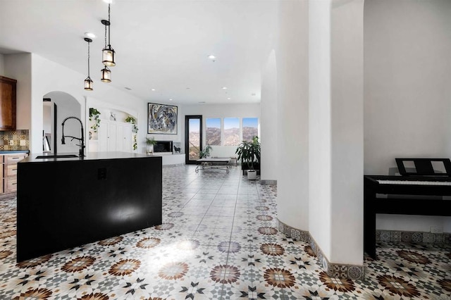 24916 Bareta Star Ranch Rd, Ramona, CA 92065 - kitchen featuring arched walkways, a sink, backsplash, hanging light fixtures, and light tile patterned floors