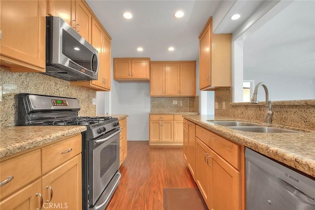 kitchen featuring a sink, light wood-type flooring, backsplash, and stainless steel appliances