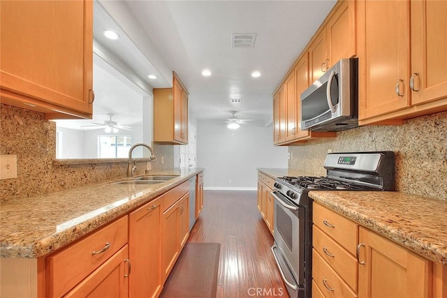 kitchen featuring visible vents, a sink, appliances with stainless steel finishes, baseboards, and dark wood-style flooring