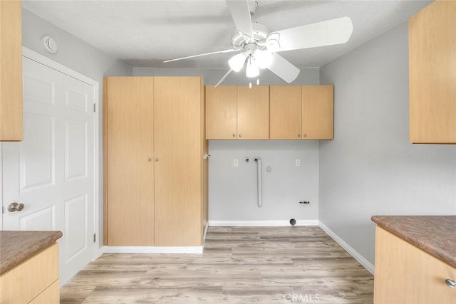 clothes washing area featuring baseboards, cabinet space, ceiling fan, washer hookup, and light wood-type flooring