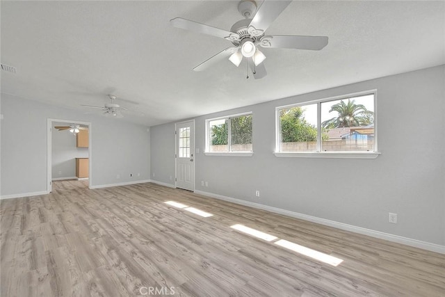 interior space featuring visible vents, baseboards, a textured ceiling, and light wood-style flooring