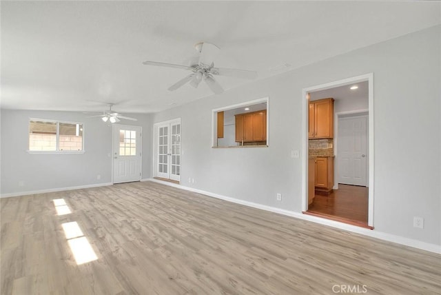 unfurnished living room featuring a ceiling fan, light wood-style floors, and baseboards