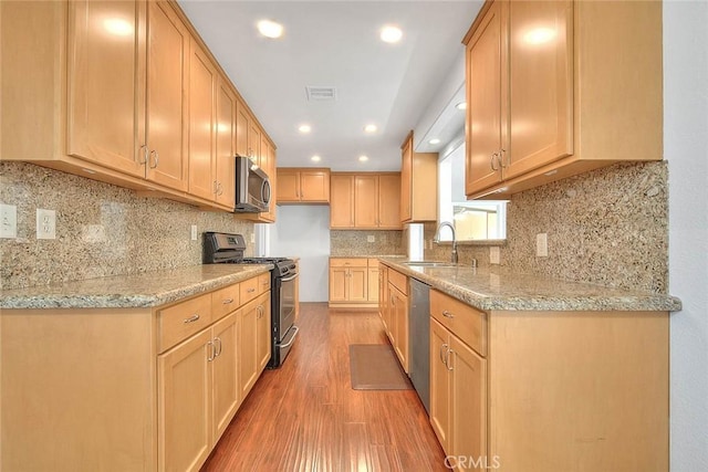 kitchen featuring visible vents, light wood-type flooring, a sink, light stone counters, and appliances with stainless steel finishes