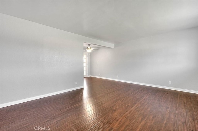 unfurnished room featuring dark wood finished floors, baseboards, and ceiling fan