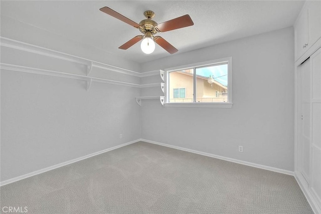 interior space featuring ceiling fan, baseboards, a closet, and light carpet