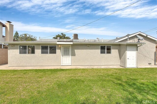 back of house featuring a lawn and stucco siding