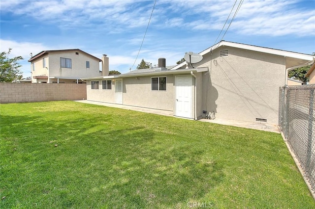 rear view of house featuring a fenced backyard, a lawn, and stucco siding