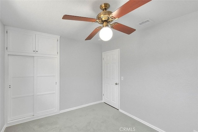 unfurnished bedroom with visible vents, baseboards, light carpet, a closet, and a ceiling fan