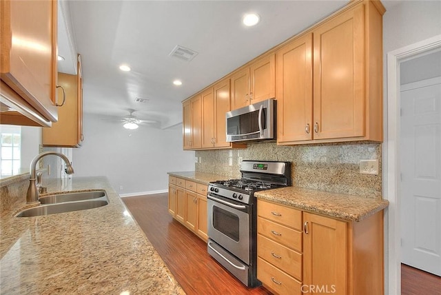 kitchen featuring visible vents, a sink, backsplash, appliances with stainless steel finishes, and dark wood-style flooring