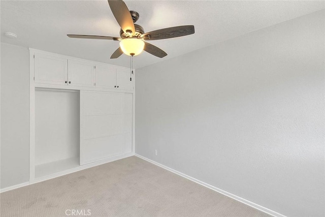 unfurnished bedroom featuring baseboards, light colored carpet, a closet, and ceiling fan