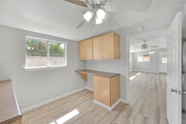 kitchen with light wood-style flooring, plenty of natural light, built in desk, and light brown cabinetry