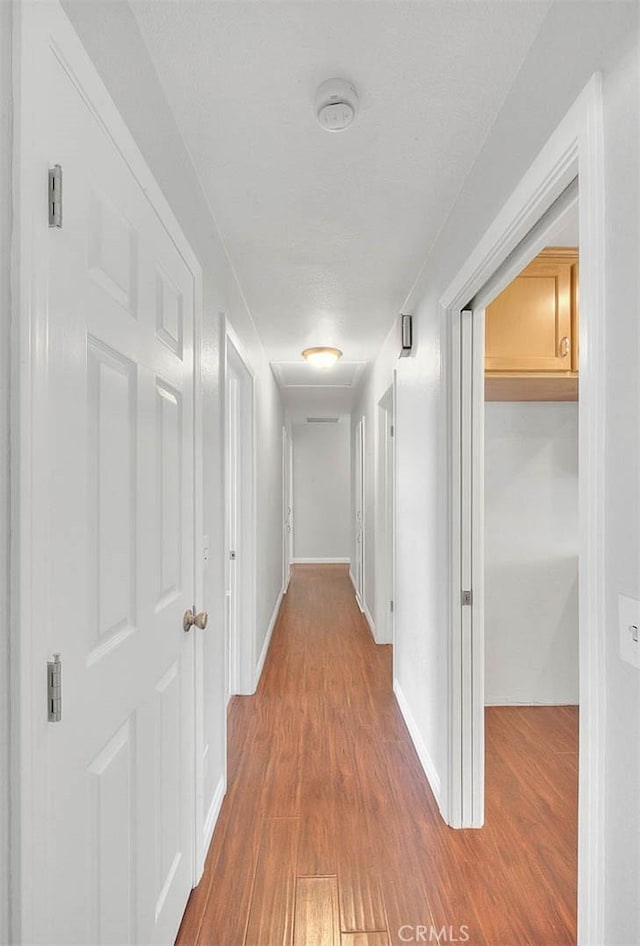 corridor with wood finished floors and baseboards