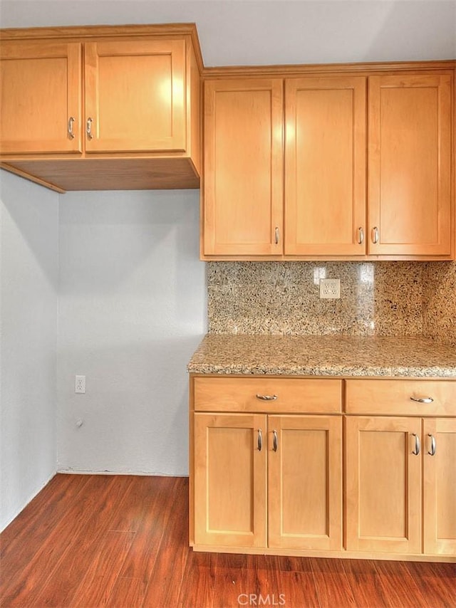 kitchen featuring light stone counters, dark wood-style floors, and backsplash