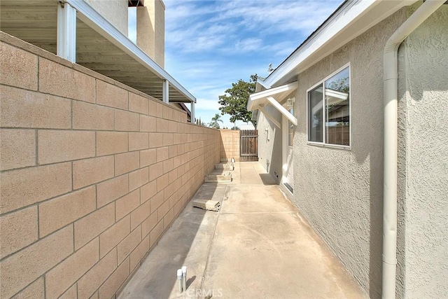 view of side of home featuring stucco siding, a patio, and fence