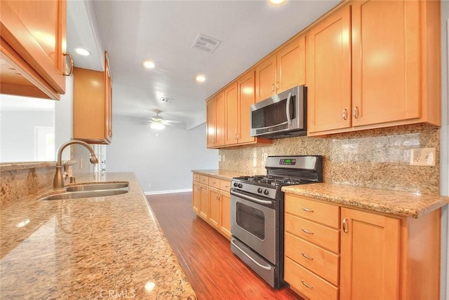 kitchen featuring visible vents, decorative backsplash, wood finished floors, stainless steel appliances, and a sink