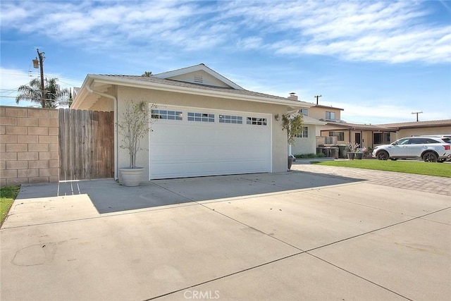 ranch-style home featuring concrete driveway, fence, a garage, and stucco siding