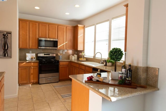 kitchen with sink, decorative backsplash, light tile patterned floors, kitchen peninsula, and stainless steel appliances