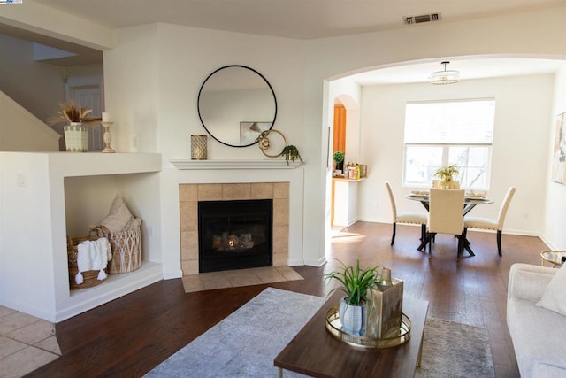 living room featuring a tiled fireplace and wood-type flooring