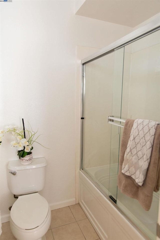 bathroom featuring tile patterned floors, toilet, and combined bath / shower with glass door