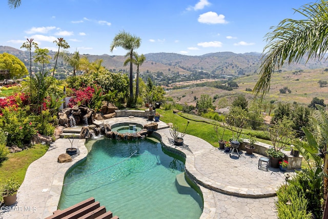 view of swimming pool featuring an in ground hot tub, a mountain view, and a patio