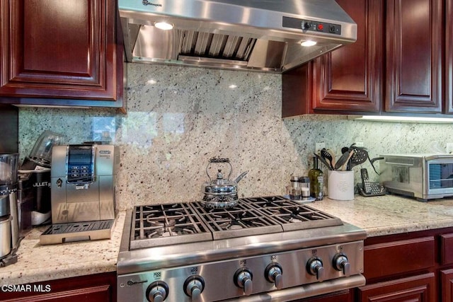 kitchen featuring light stone counters, ventilation hood, stainless steel stove, and tasteful backsplash