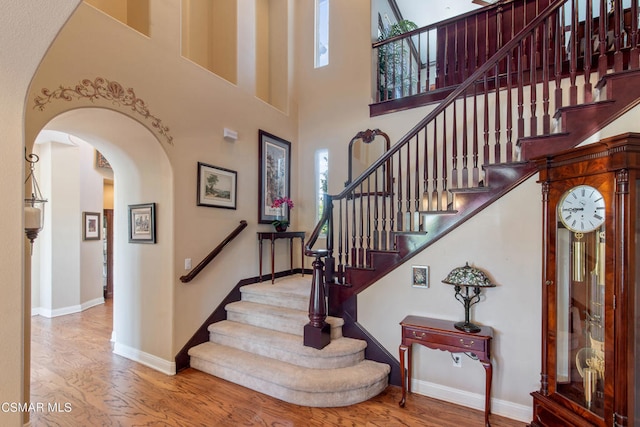 staircase with a towering ceiling and hardwood / wood-style floors