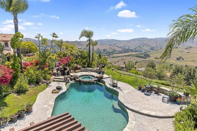 view of pool with an in ground hot tub, a mountain view, and a patio